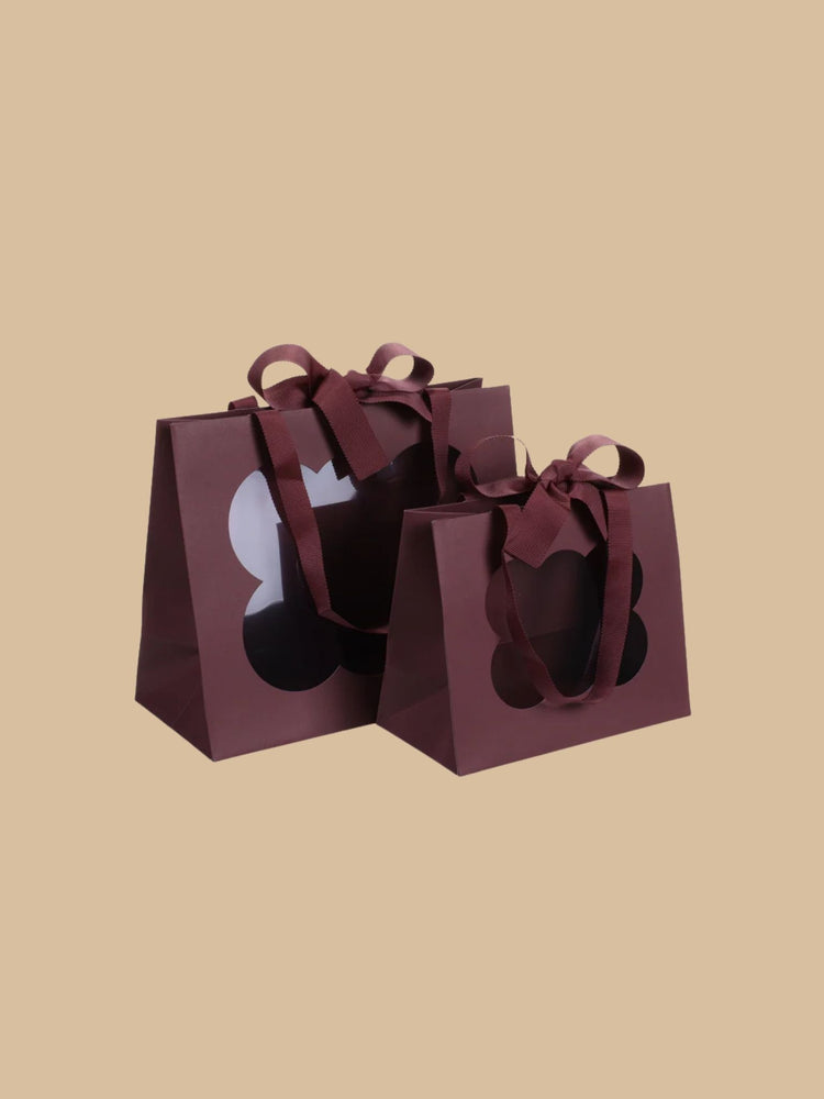 Geschenktüte in Bordeaux mit dekorativem Fenster und Schleife in klein & groß abgebildet
