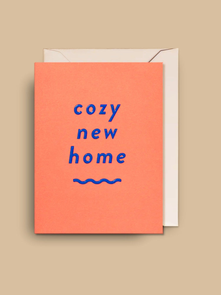 Die Mini-Grußkarte "cozy new home" (Orangefarbener Hintergrund auf blauer Schrift) mit passendem weißen Umschlag
