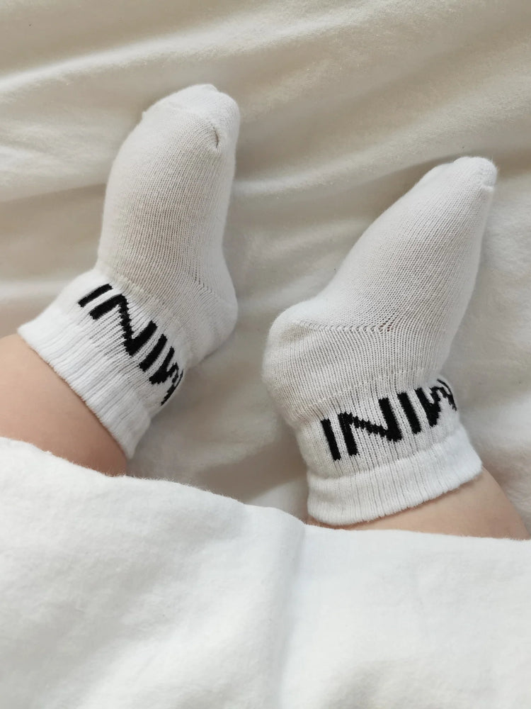 Tennissocken für Babys mit dem schlichten, schwarzen Statement "MINI"