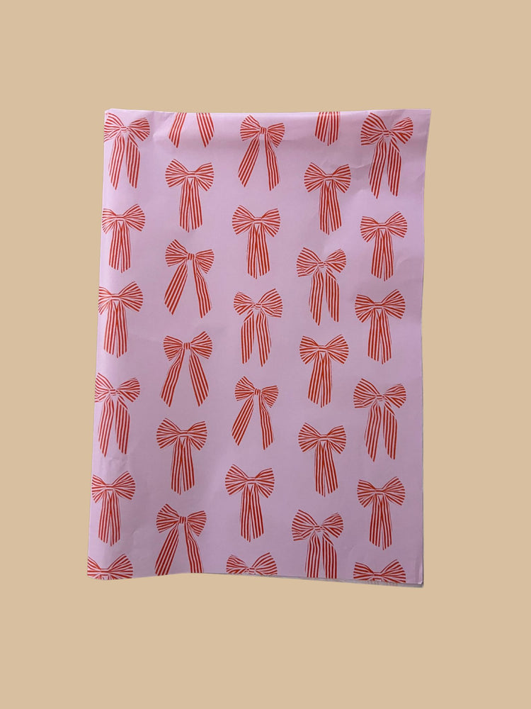 Seidenpapier orange-rote Schleifen auf rosa Hintergrund