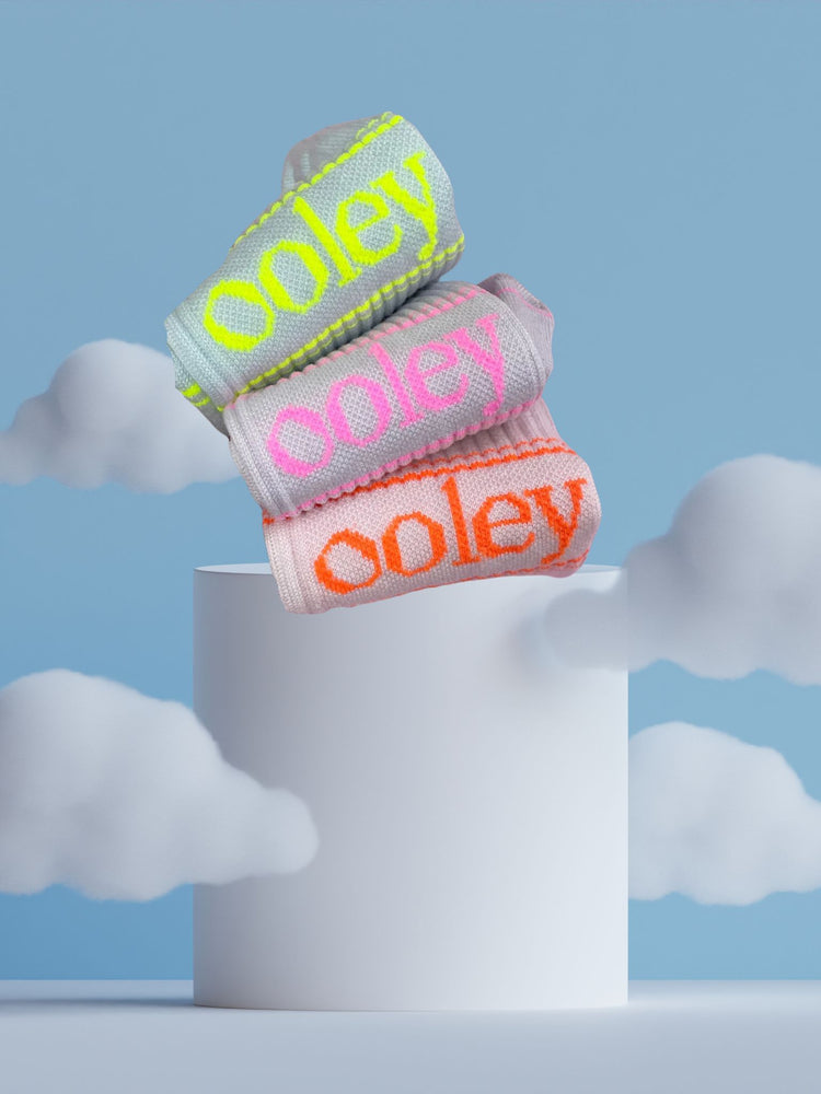 le ooley Luxury Tennissocken in Pastellfarben mit Neon kombiniert, eine Auswahl drapiert auf ein Podest mit Wolken umgeben
