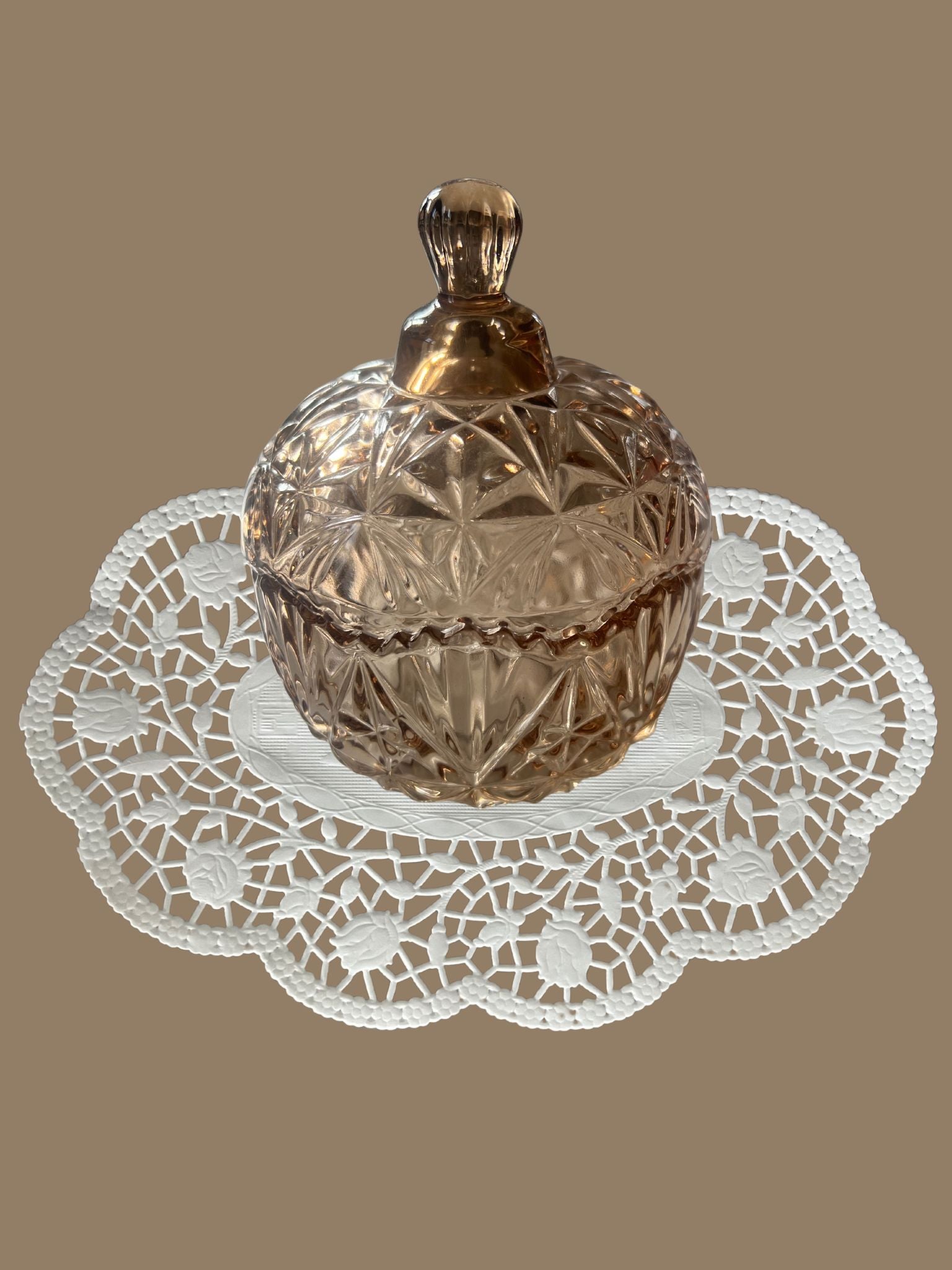 Bonbonniere mit Deckel aus Kristallglas in Hellbraun auf einem Vintage Deckchen abgebildet - klassisch und zeitlose Eleganz 