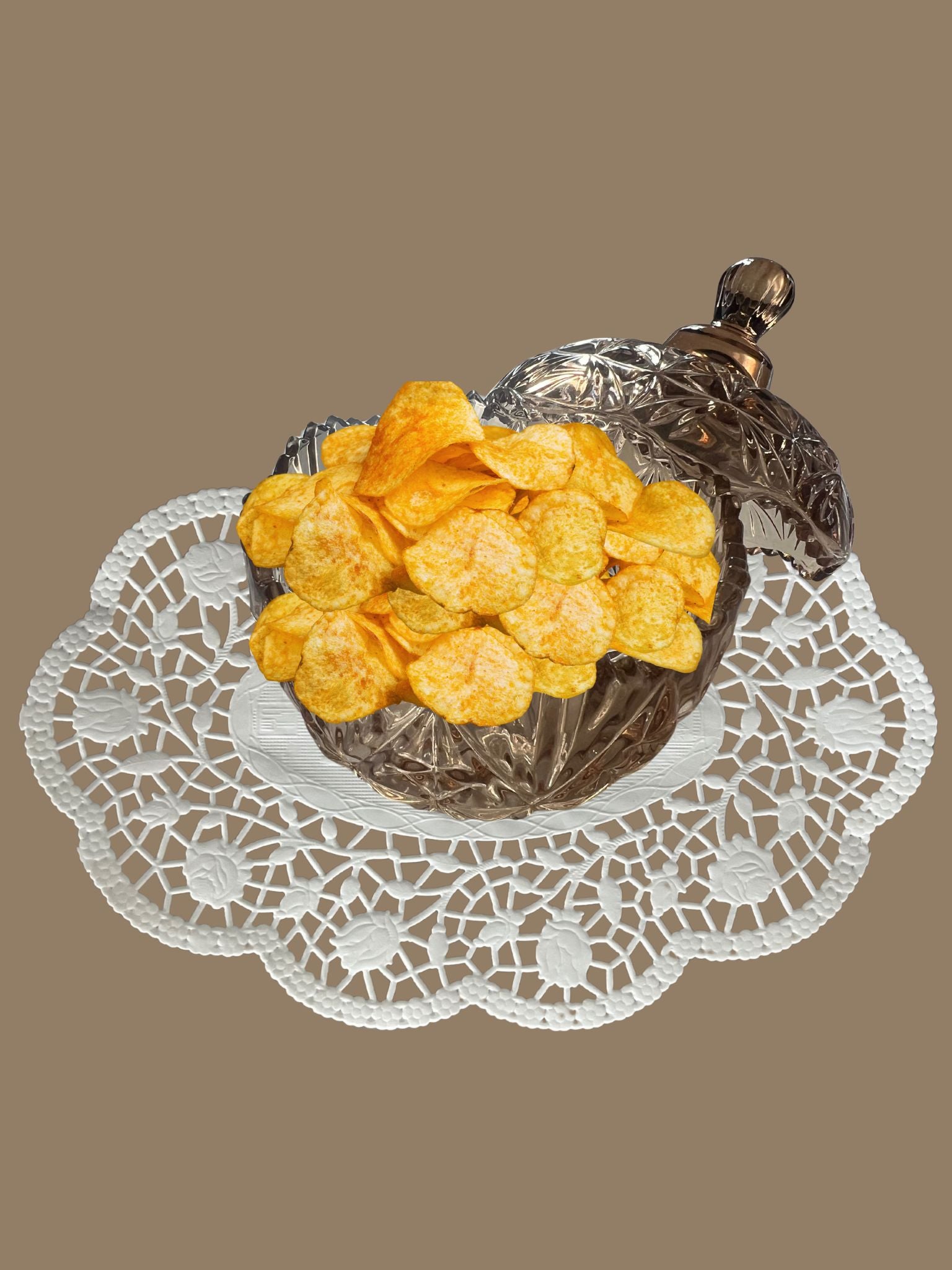 Bonbonniere mit Deckel aus Kristallglas in Hellbraun auf einem Vintage Deckchen mit Chips befüllt abgebildet - klassisch und zeitlose Eleganz 